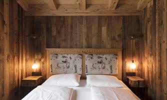 A cozy bedroom with wooden decor. The bed features a lovely headboard design and soft lighting.