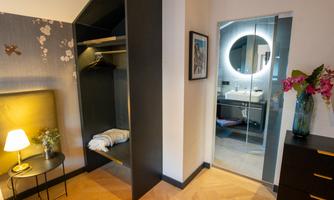 A modern room with a wardrobe and a bathroom area. Stylish decoration and soft lighting create an inviting atmosphere.