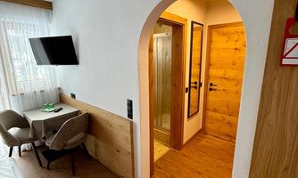 A modern hotel room with a table and chairs. In the background, there is a tastefully designed entrance to a bathroom.
