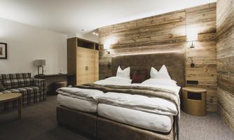A modern hotel room with a double bed and wooden walls. Cozy furniture and warm colors create an inviting atmosphere.