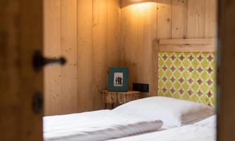 A cozy bedroom with wooden paneling and a large bed. Soft lighting creates a relaxed atmosphere.