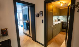 A modern hallway with two open doors. On the left side, a path leads to a living room and on the right side to a kitchen.