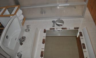 A modern bathroom with a shower and a sink. The walls are light and the furniture is functional.