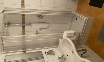A modern bathroom with a shower, sink, and a toilet. The walls are tiled and there are bright, friendly colors.