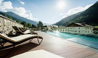 A quiet pool area with loungers and a magnificent view of the mountains. The sun shines clearly over the landscape.
