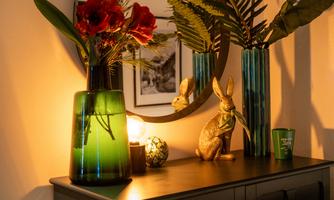 A stylish table with decorative vases, colorful flowers, and a golden bunny. The soft light creates a cozy atmosphere.