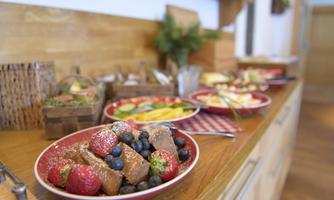 A rustic buffet arrangement with various plates. Fresh fruits like strawberries and blueberries are clearly visible.