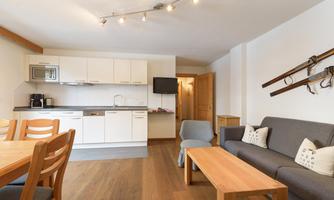 A modern apartment with an open kitchen and a cozy living area. The space is bright and cheerfully designed.