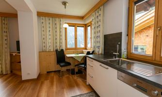 A bright and modern kitchen with wooden details and large windows. The dining area is cozy and invites you to linger.