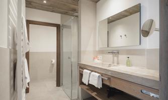 A modern bathroom with a simple design. It includes a shower, a sink area, and wooden details.