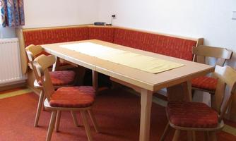 A simply furnished dining area with a table and chairs. The bench with red upholstery creates a cozy atmosphere.