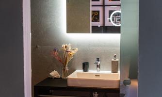 A modern bathroom with a sink and elegant lighting. Decorative flowers complement the stylish atmosphere.