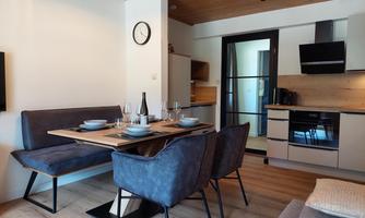 A modern kitchen with a dining area. The table is set and there are comfortable chairs available.