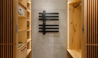 A modern entrance area with wooden shelves and a minimalist coat rack area. The walls are bright and the floor is made of gray tiles.