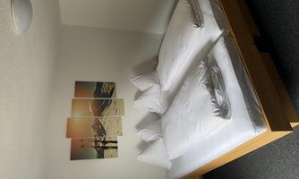 A cozy bedroom with two single beds and fresh bed linens. A picture of snowy mountains hangs on the wall.