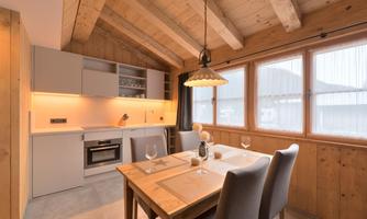 A modern kitchen unit with a wooden ceiling and a large dining area. The space is bright and inviting, with plenty of natural light coming through the windows.