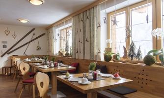 A cozy restaurant with wooden furniture and red chairs. Large windows let in plenty of light and create an inviting atmosphere.