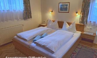 A cozy bedroom with two single beds and white bedspreads. There are window curtains and a wall art that gives the room a warm ambiance.