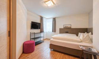 A modern bedroom with a large bed and two pillows. A television and a small table are also in the room.