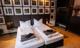 A modern bedroom with two separate beds and stylish decorations on the wall. The furnishings are elegant and cozy, with a warm atmosphere.