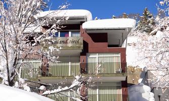 A modern building in the snow with balconies and snow-covered roofs. The clear blue sky complements the winter landscape.