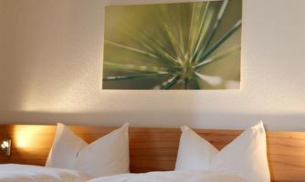 A cozy room with two beds and a modern wooden paneling. On the wall hangs a green artwork depicting nature.