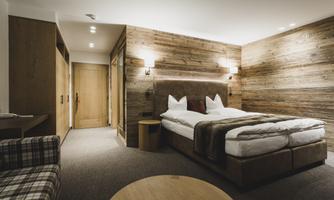 A modern bedroom with wooden walls and a cozy double bed. The decor is simple and inviting, perfect for a relaxing stay.