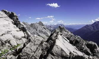 An impressive mountain landscape with rugged rocks and blue sky. The view shows majestic peaks and wide valleys.
