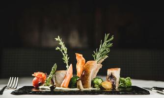 An artistically arranged plate with various types of vegetables and meat. Fresh herbs and colorful ingredients give the dish an appealing look.