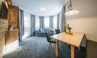 A modern living room with a cozy sofa and a table. Large windows let in plenty of daylight.