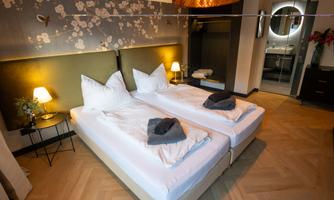 A modern bedroom with two single beds and elegant furnishings. Soft lighting and decorative elements create an inviting atmosphere.