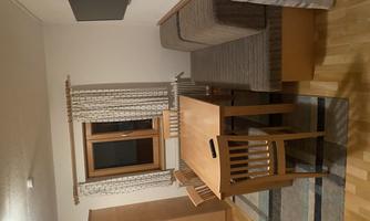 A cozy living space with a dining area. The room has a table, chairs, and a couch, as well as a window with curtains.