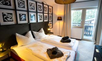 A modern room with two single beds and stylish wall pictures. Large windows let in plenty of light and create a cozy atmosphere.