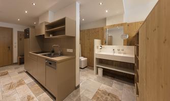 Modern kitchen with wooden shelves and an elegant sink. The room has bright tiles and a cozy atmosphere.