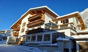 A modern building in the snow with wooden balconies. The clear blue sky gives the scene an alpine atmosphere.