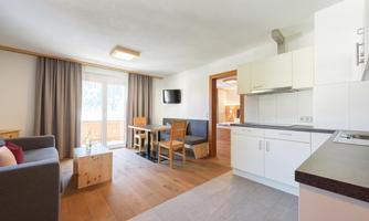 A bright apartment with a modern open living and dining area. Large windows provide a view of the outdoor area and the kitchen is well equipped.
