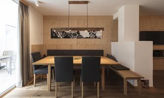 A modern dining area with a large wooden table and elegant chairs. The wooden paneling and minimalist design create a cozy atmosphere.