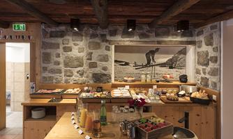 A cozy breakfast room with wooden decor and a selection of fresh dishes. In the background, there is a large photo of a landscape.