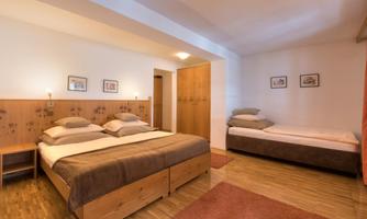 A cozy room with two sleeping areas and wooden ceilings. The furnishings are simple and bright, perfect for a relaxing getaway.