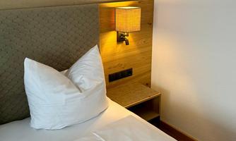 A cozy bedroom with a bed and a bedside lamp. The walls are painted in warm tones.
