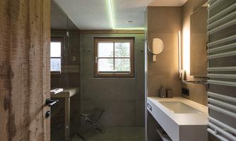 A modern bathroom with a shower, a sink, and a large window. The atmosphere is bright and inviting, featuring a wood and stone look.