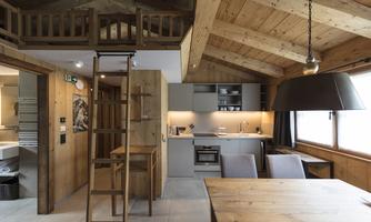 A modern apartment with wooden interior and open kitchen design. A staircase leads to a cozy upper floor.