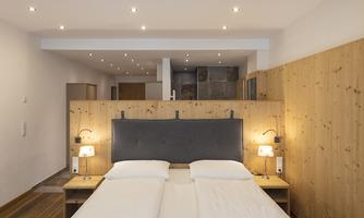 A modern bedroom with a large bed and cozy lighting. The walls are made of wood, creating a warm atmosphere.