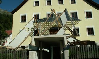 Ein gelbes Gebäude mit einer unvollendeten Dachkonstruktion. Holzrahmen stehen schief und sind sichtbar befestigt.