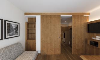A modern living room with wooden paneling and a comfortable sofa. The sliding doors and soft lighting create a warm atmosphere in the room.