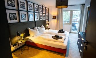 A modern bedroom with two beds and stylish decoration. Large windows let in plenty of daylight and create a pleasant atmosphere.