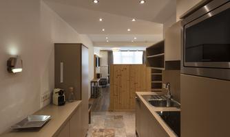 A modern kitchen with light walls and wooden details. The equipment is functional and stylish, ideal for small spaces.