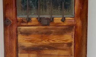A rustic wooden door with a Buddha statue and some plants in front of it. The scene radiates calm and tranquility.