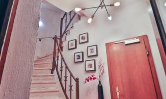 An inviting staircase with bright light and modern wall paintings. The wooden stairs lead to an upper area and feature a stylish yellow wall lamp.