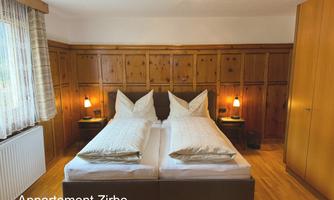 A cozy bedroom with wood paneling and two single beds. Soft lighting creates an inviting atmosphere.